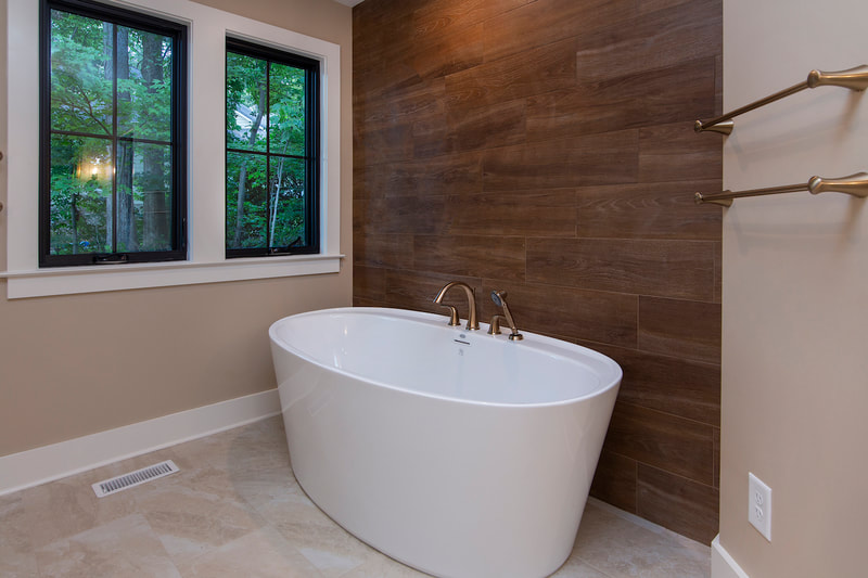 Lake Forest Lodge custom renovation master bathroom with large soaking tub by windows with views of the forest