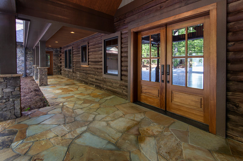 Lake Forest Lodge custom renovation entrance with covered porch, stone patio, wood doors, and windows