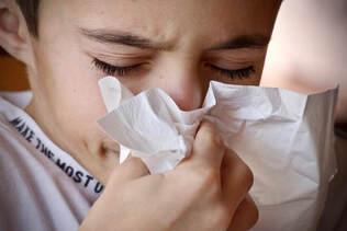 Sick little boy blowing nose in tissue