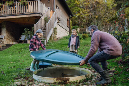 Dad and kids putting lid to septic tank onPicture