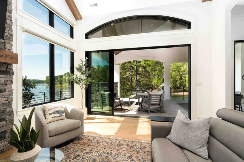 Views of lake and forest through large windows and glass sliders to covered porchPicture