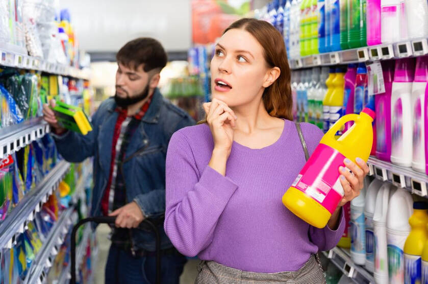 Woman and man curiously looking at ingredients of household cleaning chemicals